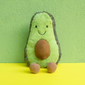 a stuffed avocado toy on a yellow surface